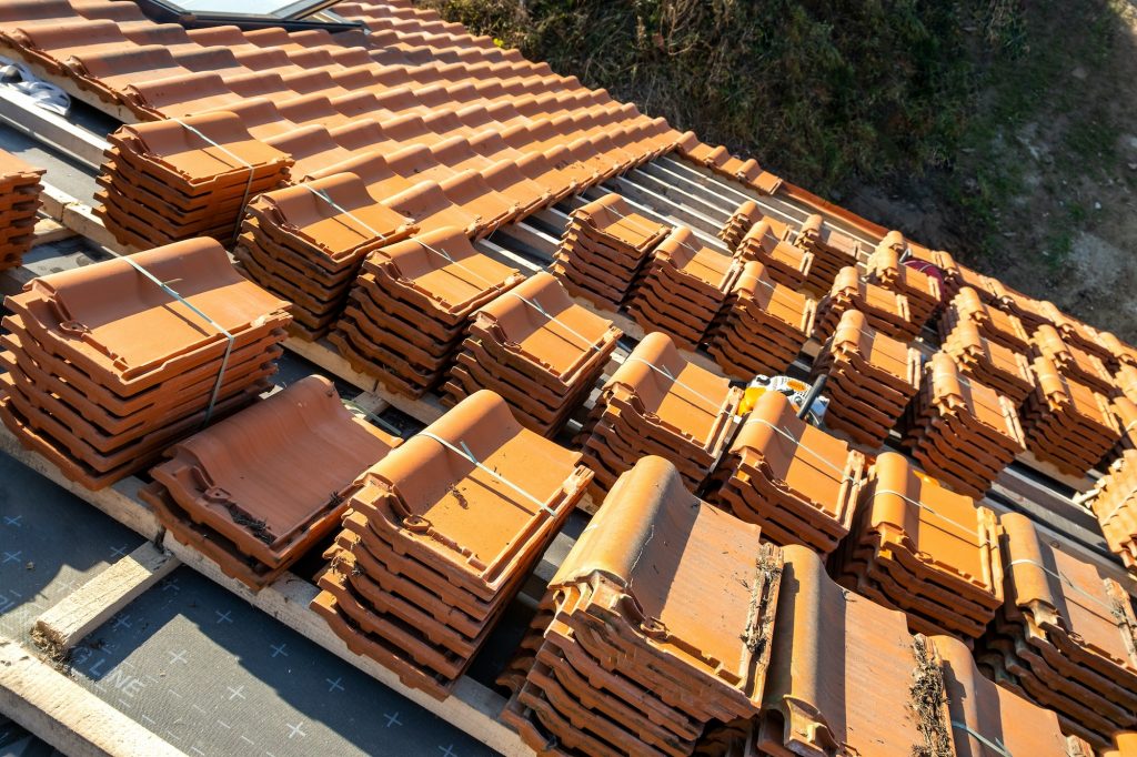 Stacks of yellow ceramic roofing tiles for covering residential building roof under construction